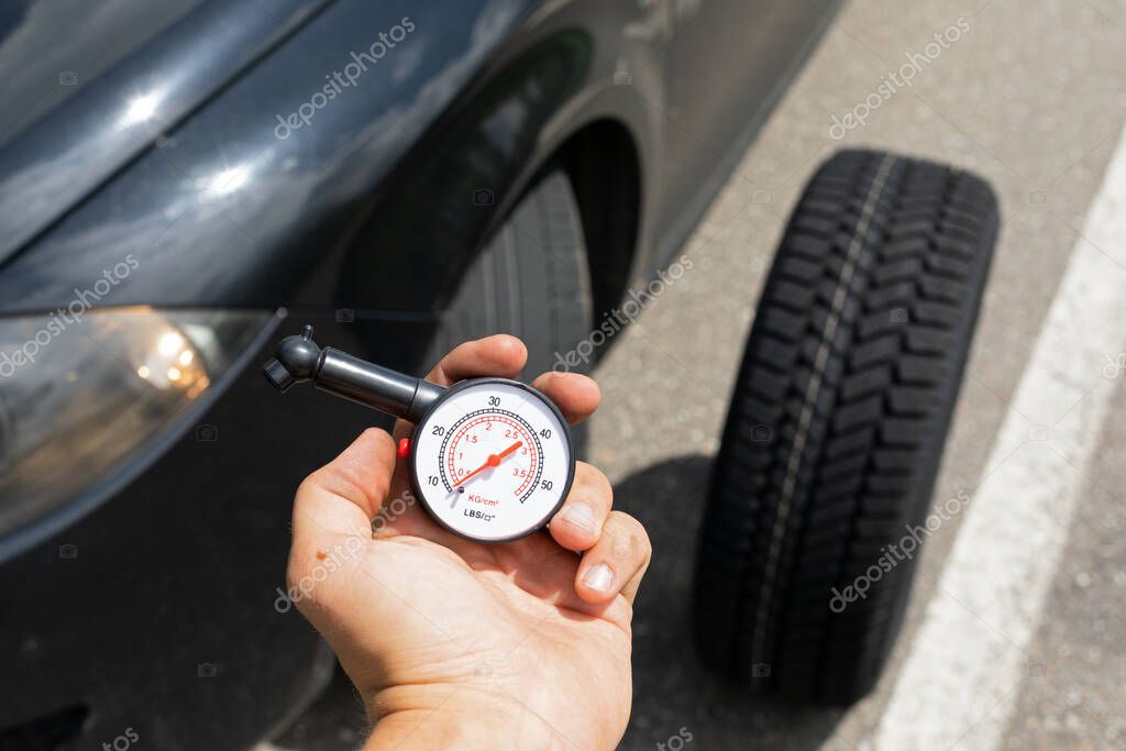 Picture of black car's brand new tyre on the road on a summer day