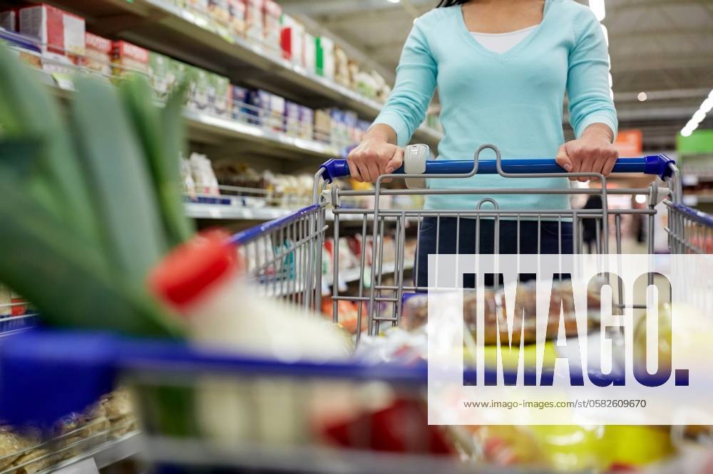 Consumerism and people concept - woman with shopping cart or trolley buying food at grocery store or supermarket. woman with food in shopping cart at supermarket ,model released, Symbolfoto; Konsumismus und Personen Konzept Frau mit Einkaufen Karren Oder Rollwagen kaufend Lebensmittel im grocery Ladengeschaeft Oder Supermarkt Frau mit Lebensmittel in Einkaufen Karren im Supermarkt ,model released, Symbolfoto ING_33594_207481