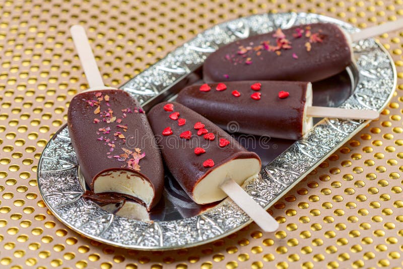 Homemade ice cream on a stick in dark chocolate icing, Artisanal vanilla ice cream on a stick in dark chocolate glaze on a metal tray, selective focus