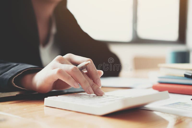 Close up Business woman using calculator and laptop for do math finance on wooden desk in office and business working background,, Close up Business woman using calculator and laptop for do math finance on wooden desk in office and business working background, tax, accounting, statistics and analytic research concept.