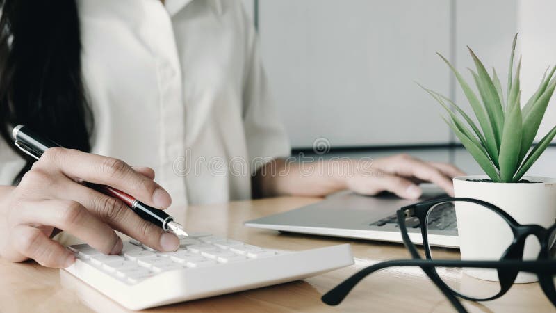 Close up Business woman using calculator and laptop for do math finance on wooden desk in office and business working background,, Close up Business woman using calculator and laptop for do math finance on wooden desk in office and business working background, tax, accounting, statistics and analytic research concept
