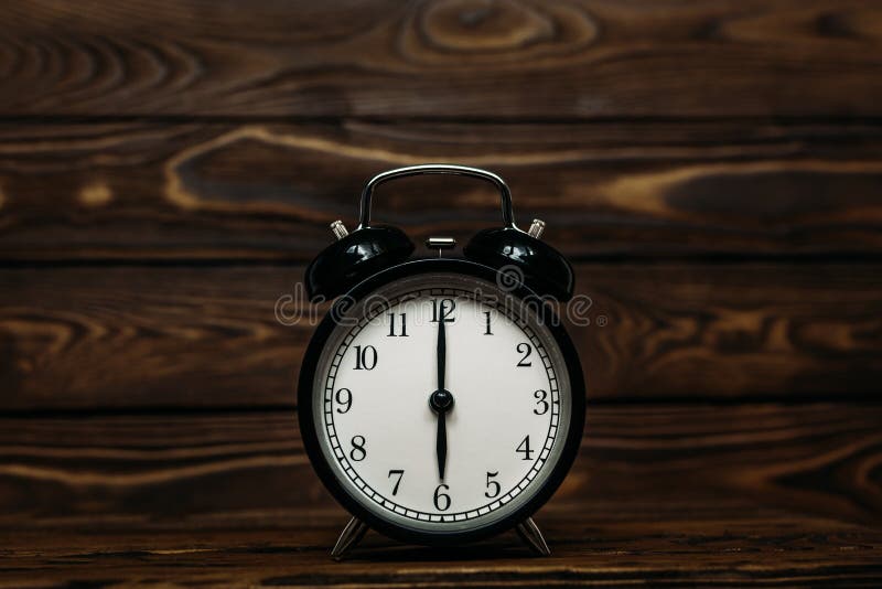 Clock on a wooden background. The clock shows the time of six o`clock in the afternoon. The clock shows the time six o`clock in, Clock on a wooden background. The clock shows the time of six o`clock in the afternoon. The clock shows the time six o`clock in the morning. An image of a retro clock showing 06:00 pm/am. Copy space