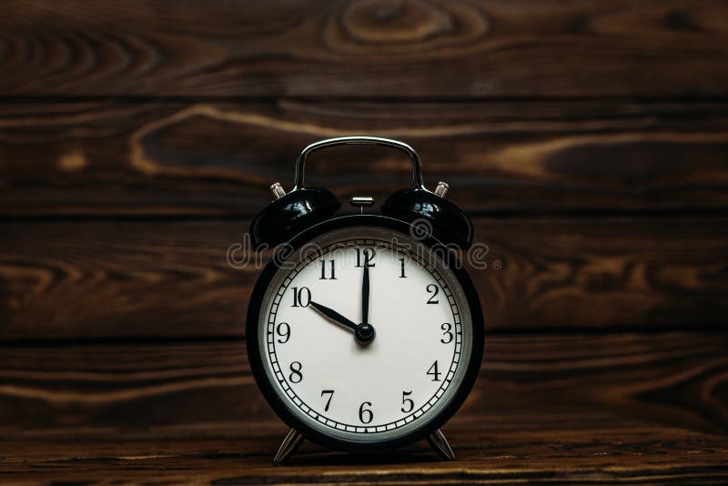 Clock on a wooden background. The clock shows the time of ten o`clock in the afternoon. Clock showing the time of ten o`clock in, Clock on a wooden background. The clock shows the time of ten o`clock in the afternoon. Clock showing the time of ten o`clock in the morning. An image of a retro clock showing 10:00 pm/am. Copy space