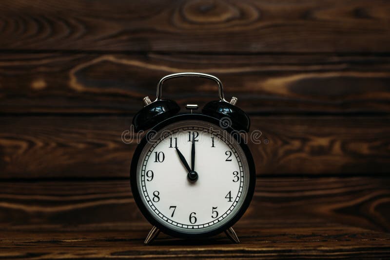 Clock on a wooden background. The clock shows the time of eleven o`clock in the afternoon. The clock shows the time of eleven o`, Clock on a wooden background. The clock shows the time of eleven o`clock in the afternoon. The clock shows the time of eleven o`clock in the morning. An image of a retro clock showing 11:00 pm/am. Copy space