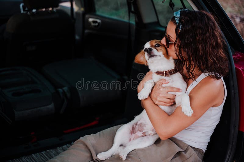 Young happy woman in a car kissing her cute dog. Travel concept, Young happy woman in a car kissing her cute dog. Travel concept model released