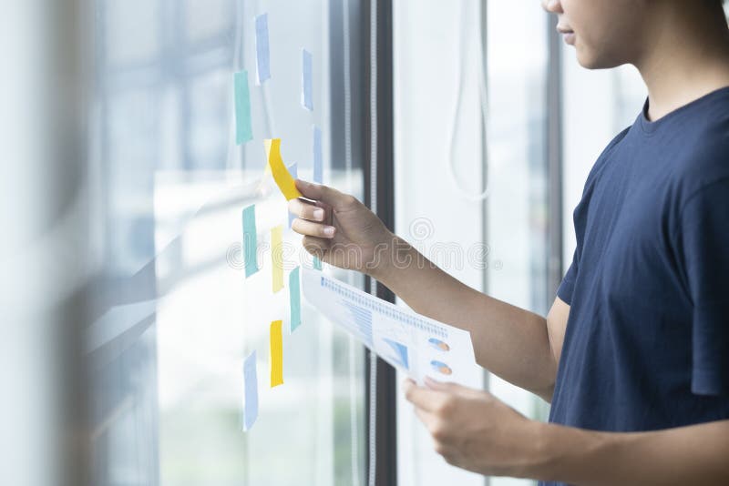 Creative man reading sticky notes on glass wall, Young creative man reading sticky notes on glass wall model released