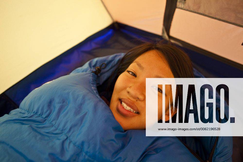 A young woman wakes up while camping in Jasper Provincial Park, Alberta, Canada acp49204