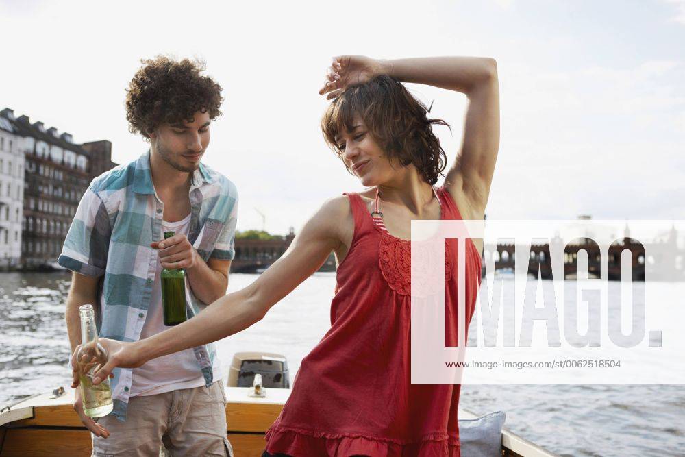 Germany, Berlin, Young couple on motorboat, man looking at woman dancing, portrait model released property released VVF00053