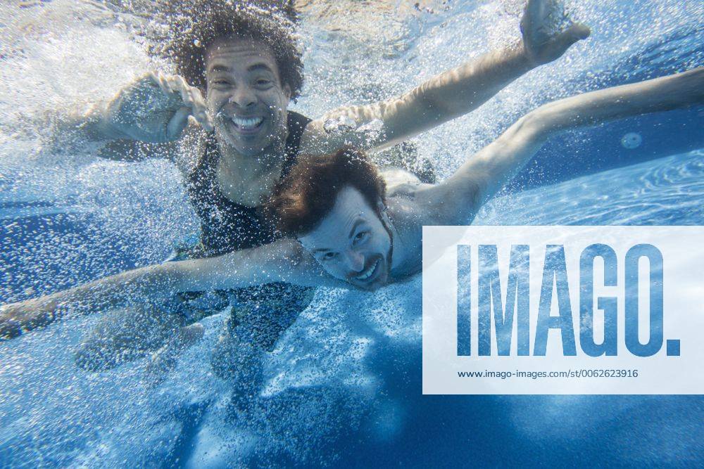 Two men swimming under water in a swimming pool. MintxImages JamelxToppin