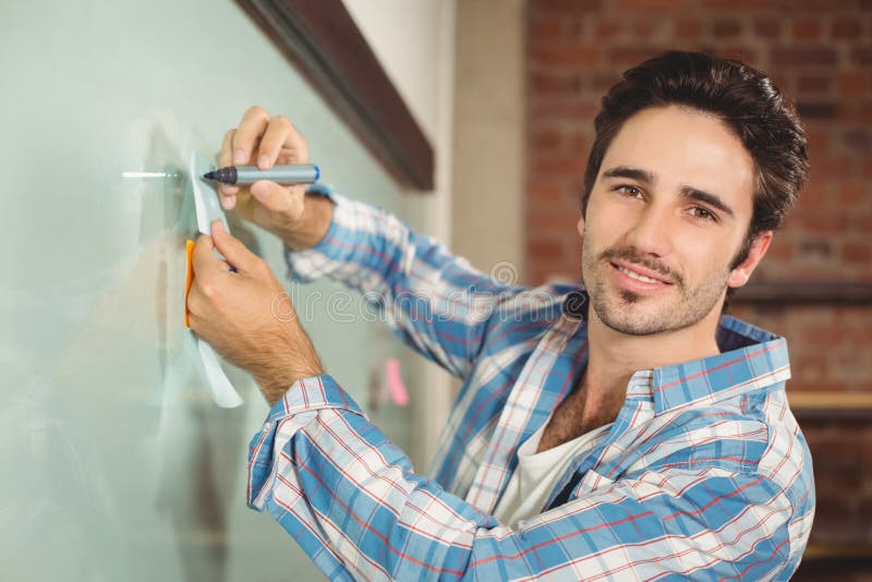 Portrait of smiling businessman holding marker and sticky notes by glass board, Portrait of smiling businessman holding marker and sticky notes by glass board in creative office model released