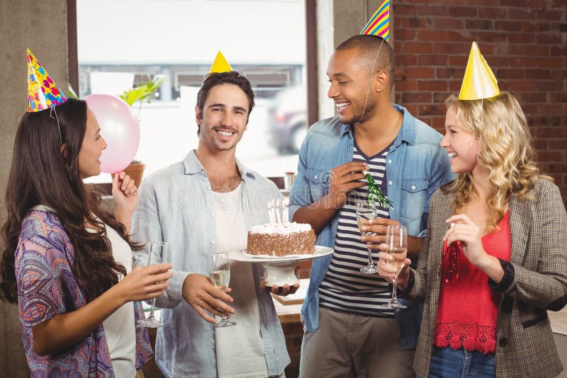 Portrait of smiling businessman holding cake during birthday celebration, Portrait of smiling businessman holding cake during birthday celebration in office
