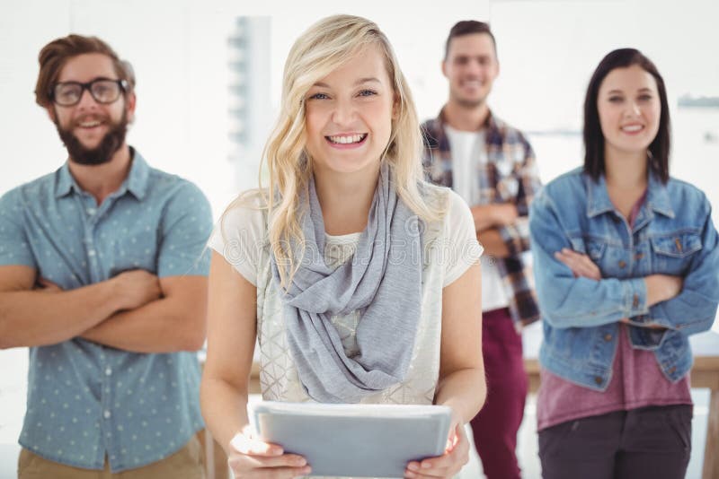 Portrait of smiling businesswoman holding digital tablet, Portrait of smiling businesswoman holding digital tablet with coworkers standing in office