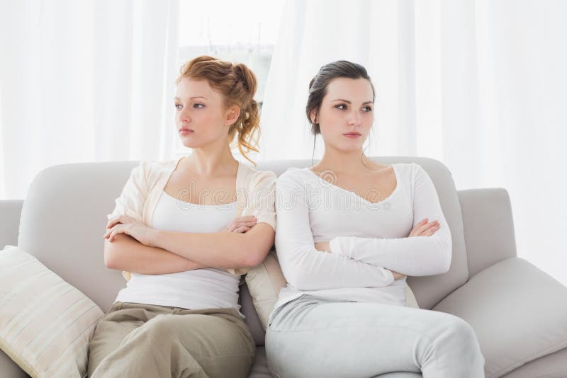 Unhappy friends not talking after argument on couch, Unhappy young female friends not talking after argument at home on the couch