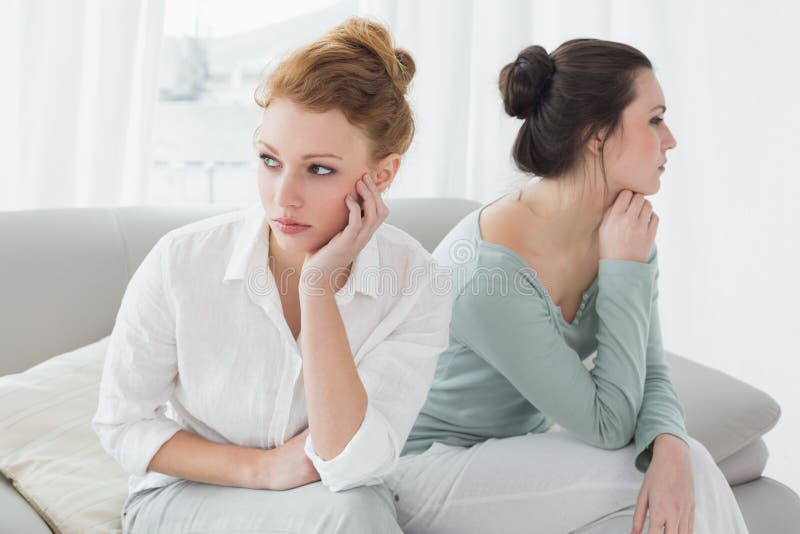 Unhappy friends not talking after argument on the couch, Unhappy young female friends not talking after argument at home on the couch
