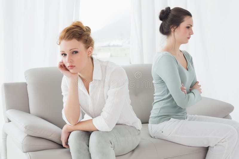 Unhappy friends not talking after argument on the couch, Unhappy young female friends not talking after argument at home on the couch