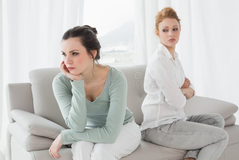 Unhappy friends not talking after argument on the couch, Unhappy young female friends not talking after argument at home on the couch