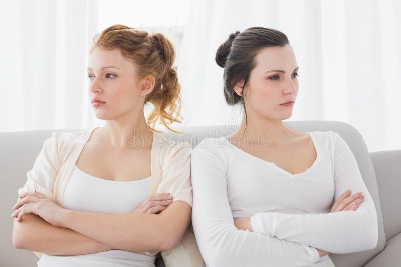 Unhappy friends not talking after argument on the couch, Unhappy young female friends not talking after argument at home on the couch