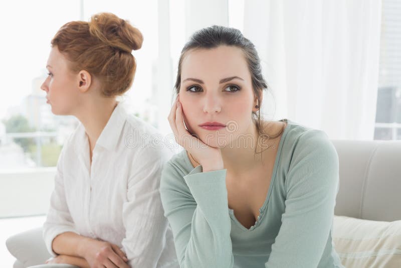 Unhappy friends not talking after argument on the couch, Unhappy young female friends not talking after argument at home on the couch