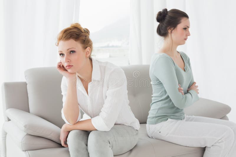 Unhappy friends not talking after argument on the couch, Unhappy young female friends not talking after argument at home on the couch