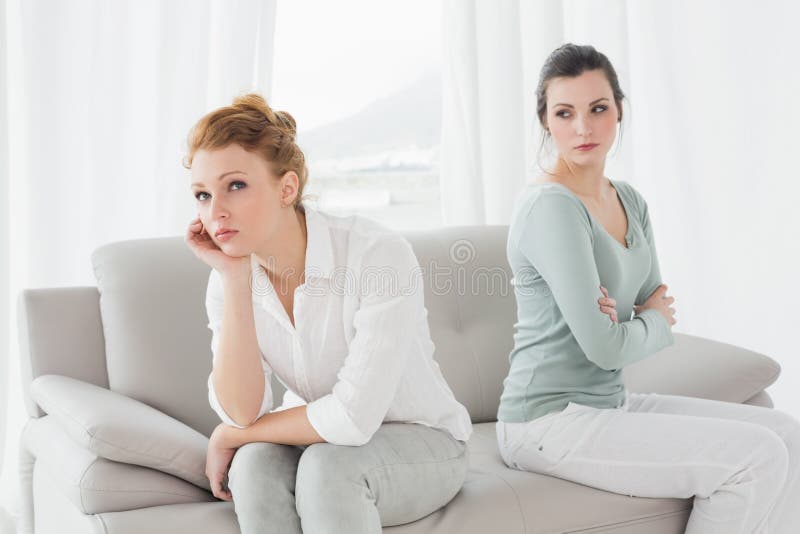 Unhappy friends not talking after argument on the couch, Unhappy young female friends not talking after argument at home on the couch