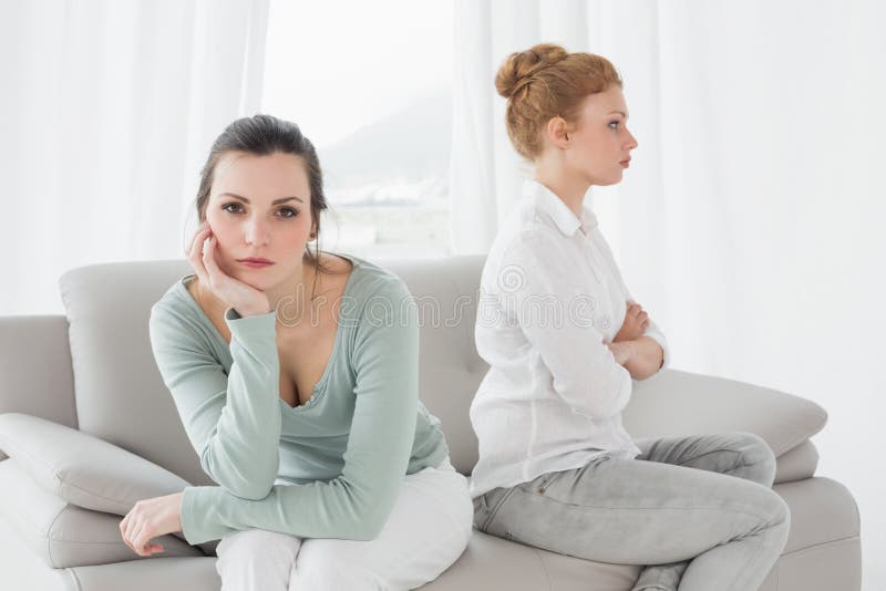 Unhappy friends not talking after argument on the couch, Unhappy young female friends not talking after argument at home on the couch