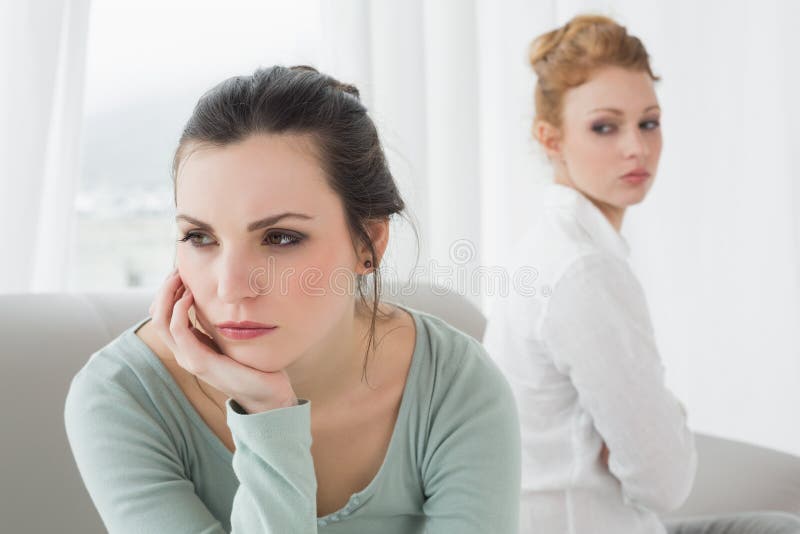 Unhappy friends not talking after argument on the couch, Unhappy young female friends not talking after argument at home on the couch