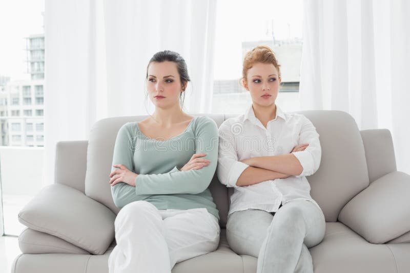Unhappy friends not talking after argument on the couch, Unhappy young female friends not talking after argument at home on the couch