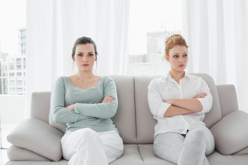 Unhappy friends not talking after argument on the couch, Unhappy young female friends not talking after argument at home on the couch