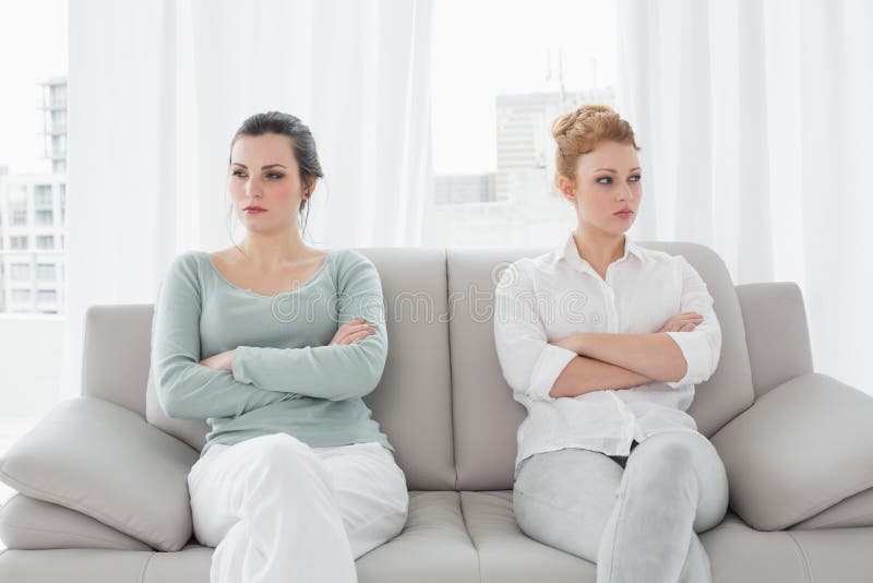 Unhappy friends not talking after argument on the couch, Unhappy young female friends not talking after argument at home on the couch
