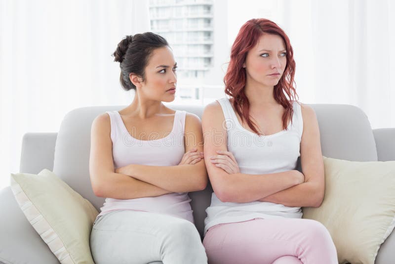 Unhappy friends not talking after argument at home, Unhappy young female friends not talking after argument at home on the couch