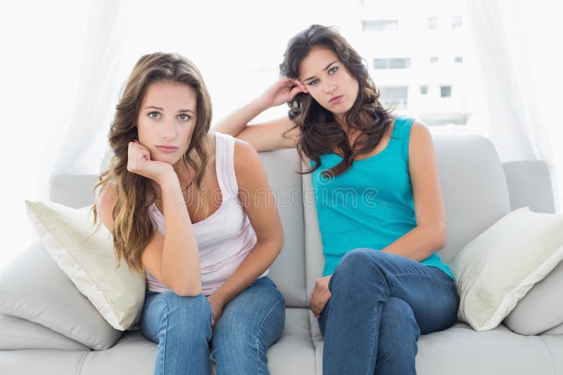 Unhappy friends not talking after argument at home, Portrait of unhappy young female friends not talking after argument at home on the couch