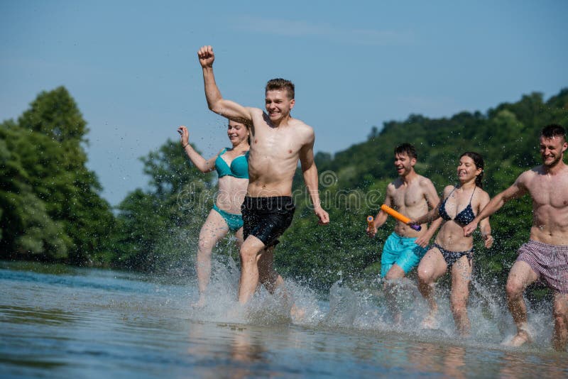 Summer joy friends having fun on river, Summer joy group of happy friends having fun while running and splashing on river