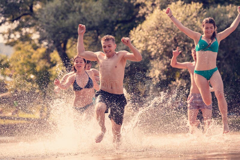 Summer joy friends having fun on river, Summer joy group of happy friends having fun while running and splashing on river
