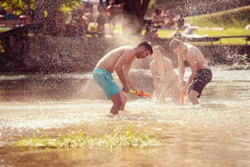 Summer joy friends having fun on river, Summer joy group of happy friends having fun while running and splashing on river