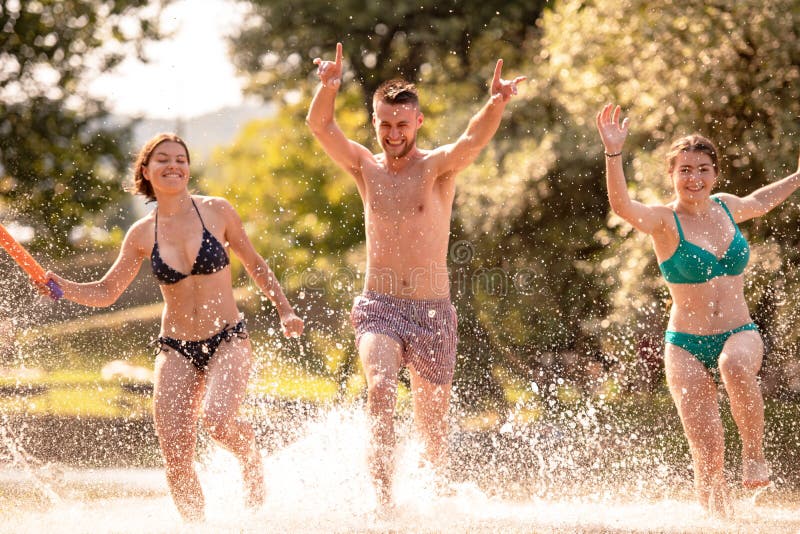 Summer joy friends having fun on river, Summer joy group of happy friends having fun while running and splashing on river