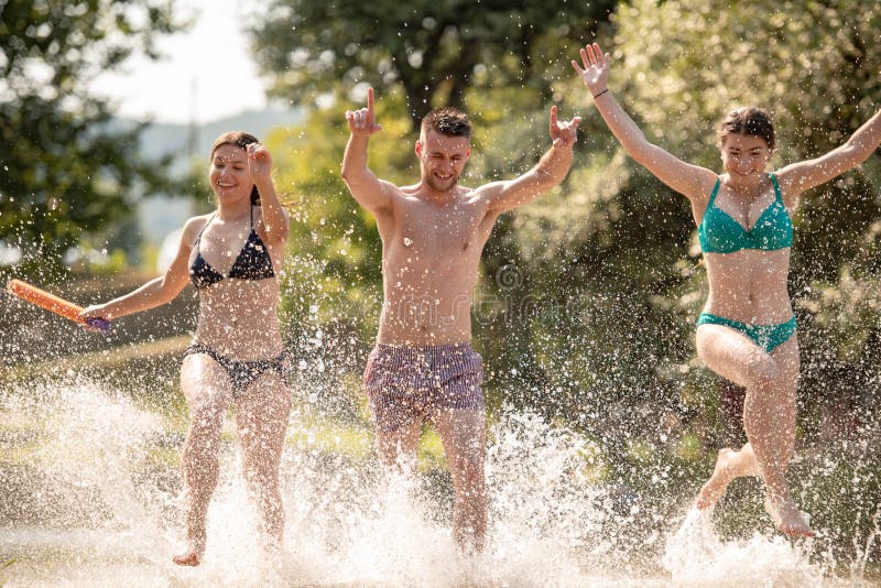 Summer joy friends having fun on river, Summer joy group of happy friends having fun while running and splashing on river
