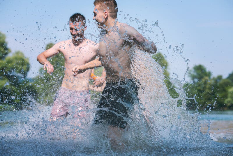 Summer joy friends having fun on river, Summer joy group of happy friends having fun while running and splashing on river