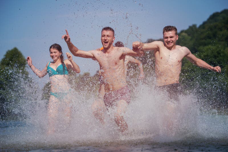 Summer joy friends having fun on river, Summer joy group of happy friends having fun while running and splashing on river