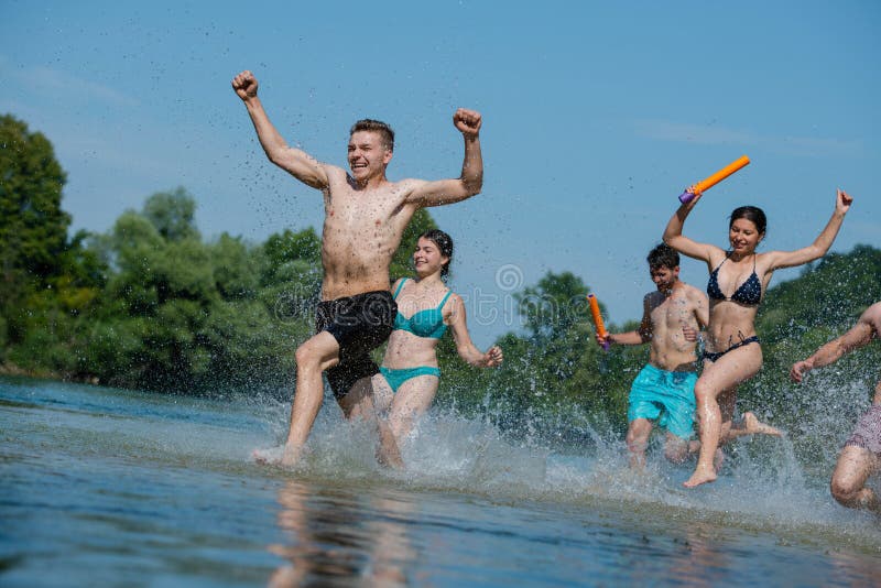 Summer joy friends having fun on river, Summer joy group of happy friends having fun while running and splashing on river