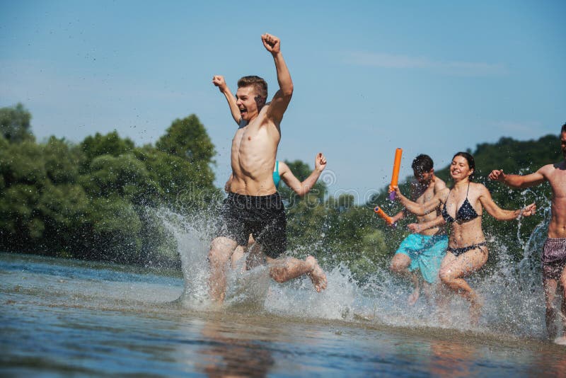 Summer joy friends having fun on river, Summer joy group of happy friends having fun while running and splashing on river