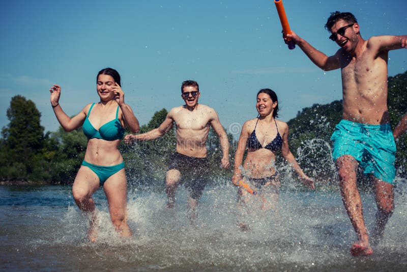Summer joy friends having fun on river, Summer joy group of happy friends having fun while running and splashing on river