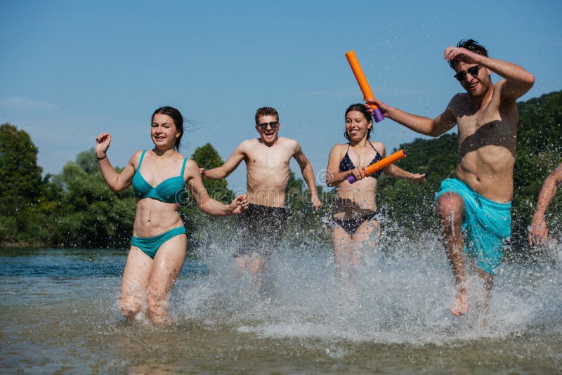 Summer joy friends having fun on river, Summer joy group of happy friends having fun while running and splashing on river
