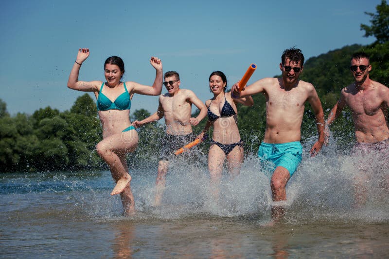Summer joy friends having fun on river, Summer joy group of happy friends having fun while running and splashing on river