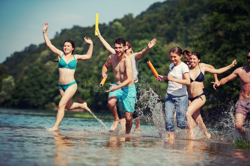 Summer joy friends having fun on river, Summer joy group of happy friends having fun while running and splashing on river