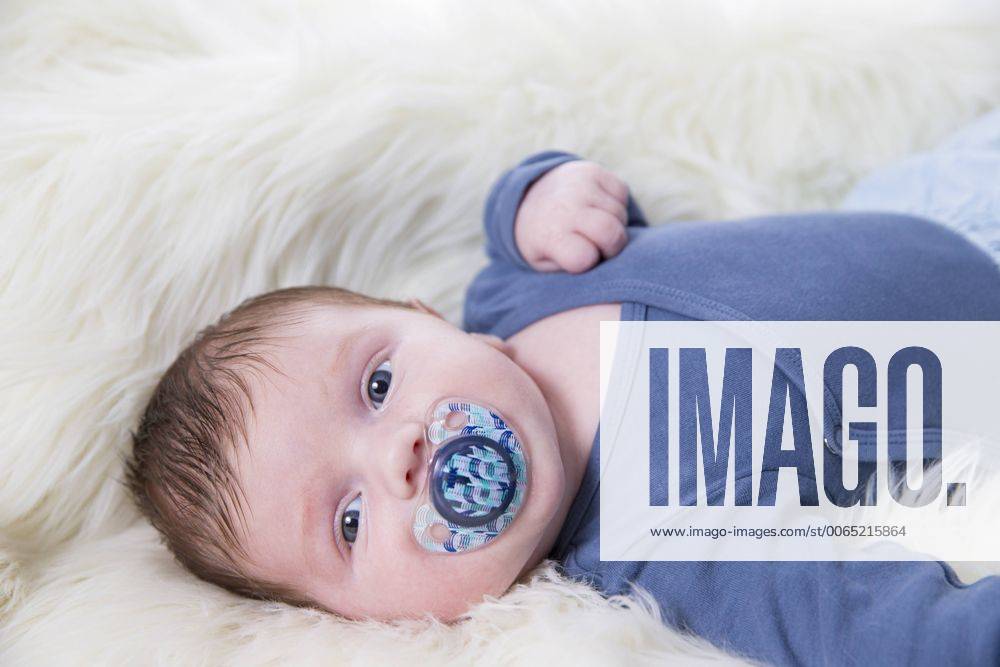 Portrait of newborn baby boy with pacifier lying on sheepskin model released Symbolfoto ROMF000057