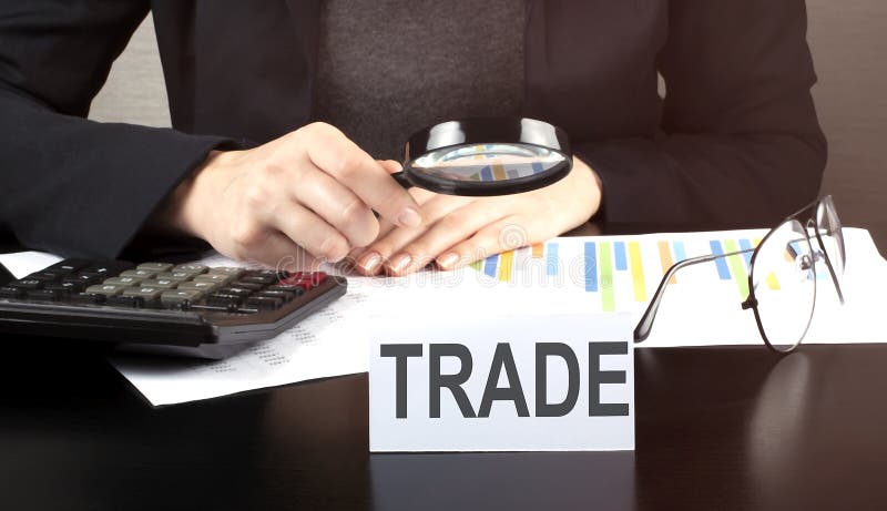 Close up Business woman using calculator and charts do math finance on wooden desk in office and business working background with, Close up Business woman using calculator and charts do math finance on the wooden desk in office and business working background with text TRADE