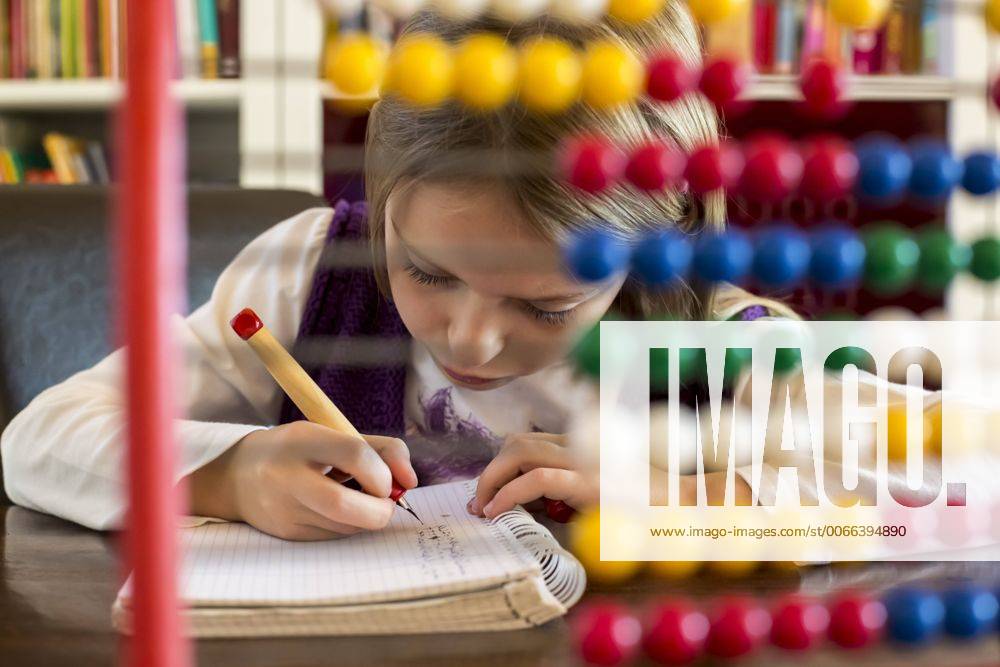IMAGO Creative: Gesellschaft, Schule, Schulanfang Girl sitting behind abacus doing homework SARF002176
