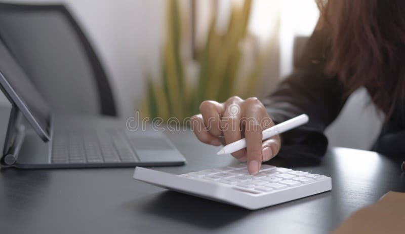 Close up Business woman using calculator and laptop for do math finance on wooden desk in office and business working background,, Close up Business woman using calculator and laptop for do math finance on wooden desk in office and business working background, tax, accounting, statistics and analytic research concept.