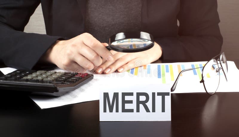 Close up Business woman using calculator and charts do math finance on wooden desk in office and business working background with, Close up Business woman using calculator and charts do math finance on the wooden desk in office and business working background with text MERIT