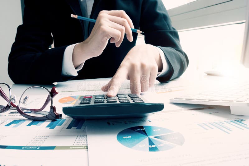 Close up Business woman using calculator and laptop for do math finance on wooden desk in office and business working background,, Close up Business woman using calculator and laptop for do math finance on wooden desk in office and business working background, tax, accounting, statistics and analytic research concept